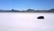 Cinematic aerial drone shot of silver minivan car driving in the middle of atmospheric Bonneville salt lake desert flats