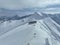 Cinematic Aerial Epic scene of group of skiers and snowboarders on top of a mountain. Winter at the summit peak or top