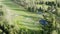 Cinematic aerial footage over colorful green golf course - few unidentified people play golf. Vibrant colors, drone footage