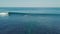 Cinematic aerial view over a surfer riding a breaking wave in the ocean at summer.