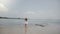 Cinematic background shot of happy little 6-8 year old girl in straw hat watching epic scenery at exotic ocean beach.