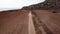 Cinematic footage - Car crossing red desert land throwing sand and dirt in the air surrounded by sea.