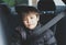 Cinematic portrait boy siting in safety car seat looking at camera with smiling face,Child sitting in the back passenger seat with