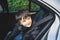 Cinematic portrait boy siting in safety car seat looking at camera with smiling face,Child sitting in the back passenger seat with