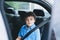 Cinematic portrait boy siting in safety car seat looking at camera with smiling face,Child sitting in the back passenger seat with