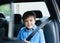 Cinematic portrait boy siting in safety car seat looking at camera with smiling face,Child sitting in the back passenger seat with