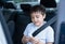 Cinematic portrait mixed race boy siting in safety car seat reading on paper with smiling face,Child sitting in the back passenger