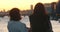 Cinematic portrait of mother and daughter talking and admiring sunset together. View from behind.