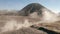 Cinematic shot aerial view of motocross rider driving in a volcanic dusty desert near beautiful Mount Bromo in East Java