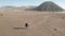 Cinematic shot aerial view of tourists walking in a volcanic dusty desert near beautiful Mount Bromo in East Java