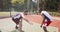 Cinematic shot of two diverse basketball players practicing tricks at outdoor streetball court together, tracking shot