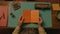 Cinematic Still Of Bookworm Reading Orange Book On Table In Wes Anderson Style