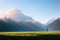 Cinematic and surreal image of a woman walking through green meadows at sunset with blue mountains in the background,