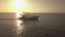 Cinematic view of a boat sailing across the sea on bright sunrise.