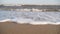 Cinematic white foamy waves crashing on the sandy shore. Amazing seascape of water surface texture. Sand is washed by