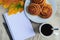 Cinnamon buns with topping on plate, cup of coffee, open notepad and pen, autumn leaf on table