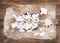 Cinnamon rolls with cream cheese icing on piece of oily craft paper over rustic wooden background