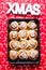 Cinnamon rolls ready to be eaten for christmas holiday, top view over a red textile with christmas design, with a  giant xmas
