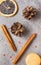 Cinnamon sticks, cones,  beige French macaroon cookies,  slice of dried orange, on a gray background
