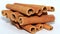 Cinnamon sticks on a white background stacked like logs.