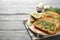 Circle board with toasted garlic bread on wooden background