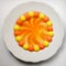 Circle of colored candies on white plate. Round yellow and orange candies melting in water, forming a circle gradient