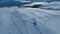 Circle fly around snow mobile with carriage trailer, aerial video of winter sunset in lifeless snowy mountains. The shot is taken