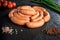 circle set of uncooked short sausages on black background
