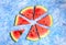 A circle of sliced triangles of watermelon on a blue solid background , the concept of minimalism