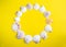 Circle of white seashells on yellow background