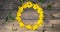 A Circle of yellow daisies on a wooden table