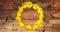 A Circle of yellow daisies on a wooden table with a mug of tea in the middle