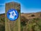 A circular, blue and white sign fixed to a weathered wooden post points the way of the Northumberland Coast Path