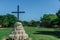 Circular concrete shrine painted in white at Trancoso, Porto Seguro, with a cross over it, in front of a grass field