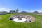 Circular fire pit surrounded by rocks in the middle of the grassy yard of a home