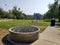 Circular metal barbeque grill on cement near grass