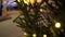 Circular movement of camera around row of Christmas trees decorated yellow luminous garlands on background of Christmas