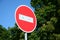 A circular red sign with a white bar indicating NO ENTRY on a grey metal post