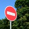 A circular red sign with a white bar indicating NO ENTRY on a grey metal post