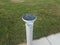 Circular solar panel light with bird poop and sidewalk and green grass