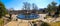 A circular stone pool with yellow winter grass, bare winter trees and lush green plants with a view of the scrapers and buildings