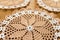 Circular towels made in crochet in white and beige colors on wooden background