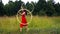 A circus performer, a young woman in a red dress, presents a performance with a hula Hoop against the background of a forest.