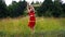 A circus performer, a young woman in a red dress, presents a performance with a hula Hoop against the background of a forest.