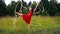 A circus performer, a young woman in a red dress, presents a performance with a hula Hoop against the background of a forest.