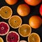 Citrus flatlay on dark rustic background. Sliced and whole oranges and grapefruits.