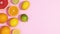 Citrus fresh fruits appear on left side of bright pink background. Stop motion flat lay