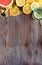 Citrus fresh summer fruits and water glass on brown wooden background, vertical