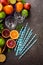 Citrus fruits, glass, straws and mint over dark background