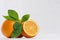 Citrus with half juicy oranges and green leaves closeup on white wood table.